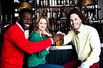 Three Friends In Bar Enjoying Beer Stock Photo