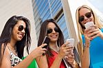 Three Girls Chatting With Their Smartphones At The Campus Stock Photo