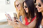 Three Girls Chatting With Their Smartphones At The Campus Stock Photo