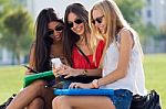 Three Girls Chatting With Their Smartphones At The Campus Stock Photo