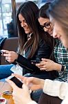 Three Young Woman Using Mobile Phone At Cafe Shop Stock Photo