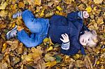 Toddler Blond Boy With Blue Eyes Lays On Bed Of Autumn Fallen Le Stock Photo