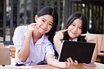 Two Asia Thai High School Student Uniform Best Friends Beautiful Girl Using Her Tablet And Funny Stock Photo