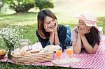 Two Asian Girlfriends Lying On The Lawn, Women In Park During Th Stock Photo