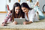 Two Beautiful Young Woman Friends Using Digital Tablet At Home Stock Photo