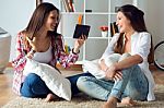 Two Beautiful Young Woman Friends Using Digital Tablet At Home Stock Photo