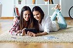 Two Beautiful Young Woman Friends Using Digital Tablet At Home Stock Photo