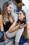 Two Students Having Fun With Smartphones After Class Stock Photo