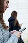 Two Young Businesswoman Using Mobile Phone In The Street Stock Photo