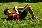 Urban Athlete Doing Stretching Exercises On The Grass Stock Photo