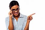 Woman Adjusting Her Spectacles And Pointing Away Stock Photo