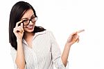 Woman Adjusting Her Spectacles And Pointing Away Stock Photo