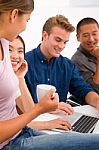 Woman Drinking Coffee With Her Friends Using Laptop Stock Photo