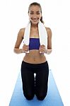 Woman In Gym Wear Kneeling On Blue Mat Stock Photo