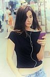 Woman Listens Music And Walks On The Street Stock Photo