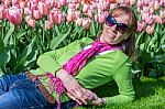 Woman Lying In Front Of Pink Tulip Field Stock Photo