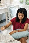 Woman Pouring Tea From The Teapot Into A White Ceramic Cup Stock Photo