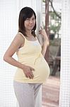 Woman Pregnant Standing Beside Home Door And Looking To Camera Stock Photo