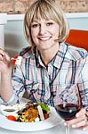 Woman Relishing Her Meal With Red Wine Stock Photo