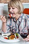 Woman Relishing Her Meal With Red Wine Stock Photo