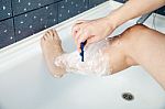 Woman Shaving Her Leg In The Bathroom Stock Photo