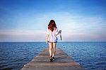 Woman Walking On Wooden Bridge Extended Into The Sea Stock Photo