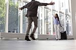 Woman With Luggage Waving To Boyfriend At Airport Stock Photo