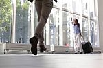 Woman With Luggage Waving To Boyfriend At Airport Stock Photo