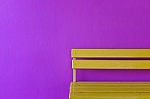 Yellow Wood Bench On Vivid Violet Wall Background Stock Photo