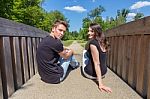 Young Attractive Dutch Couple Sitting On Wooden Bridge Stock Photo