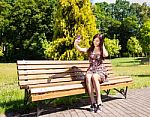 Young Beautiful Brunette Makes Selfie Sitting On A Bench Stock Photo