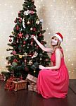 Young Beautiful Girl In Santa Hat Near Christmas Tree Stock Photo