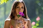 Young Beautiful Girl Smells Flowers, Against Green Summer Garden Stock Photo