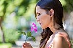 Young Beautiful Girl Smells Flowers, Against Green Summer Garden Stock Photo