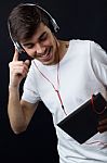 Young Beautiful Man Listening To Music. Isolated On Black Stock Photo