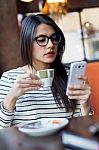 Young Beautiful Woman Using Her Mobile Phone In Coffee Stock Photo