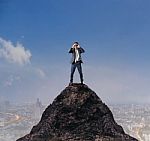 Young Business Man Standing On Top Of Mountain And Spying By Bin Stock Photo