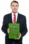 Young Businessman Showing Big Green Calculator Stock Photo