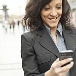 Young Businesswoman With Smartphone Walking On City Stock Photo