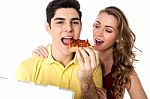 Young Couple Sharing A Pizza Slice Stock Photo