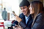 Young Couple Using Mobile Phone In Cafe Stock Photo