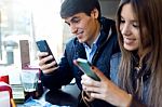 Young Couple Using Mobile Phone In Cafe Stock Photo