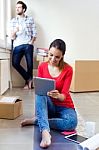 Young Couple With Digital Tablet Resting In Their New Home Stock Photo