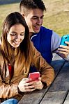 Young Couple With Smartphones In The Park Stock Photo