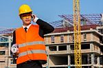 Young Engineer In Orange Shirt Stands Holding A Blueprint And Ta Stock Photo