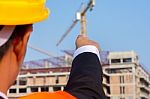 Young Engineer In Orange Shirt Stands Pointing At A Building Bei Stock Photo