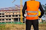 Young Engineer Wearing Orange Shirt Stands Holding A Hat And A B Stock Photo