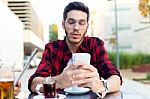 Young Entrepreneur Using His Mobile Phone At Coffee Shop Stock Photo