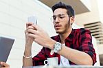 Young Entrepreneur Using His Mobile Phone At Coffee Shop Stock Photo