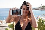 Young Female At The Seashore Taking Selfie Stock Photo